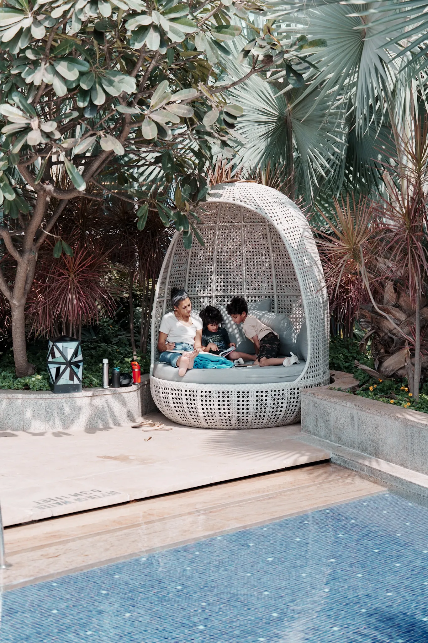 A mother reading with children in a quiet nook by the pool.