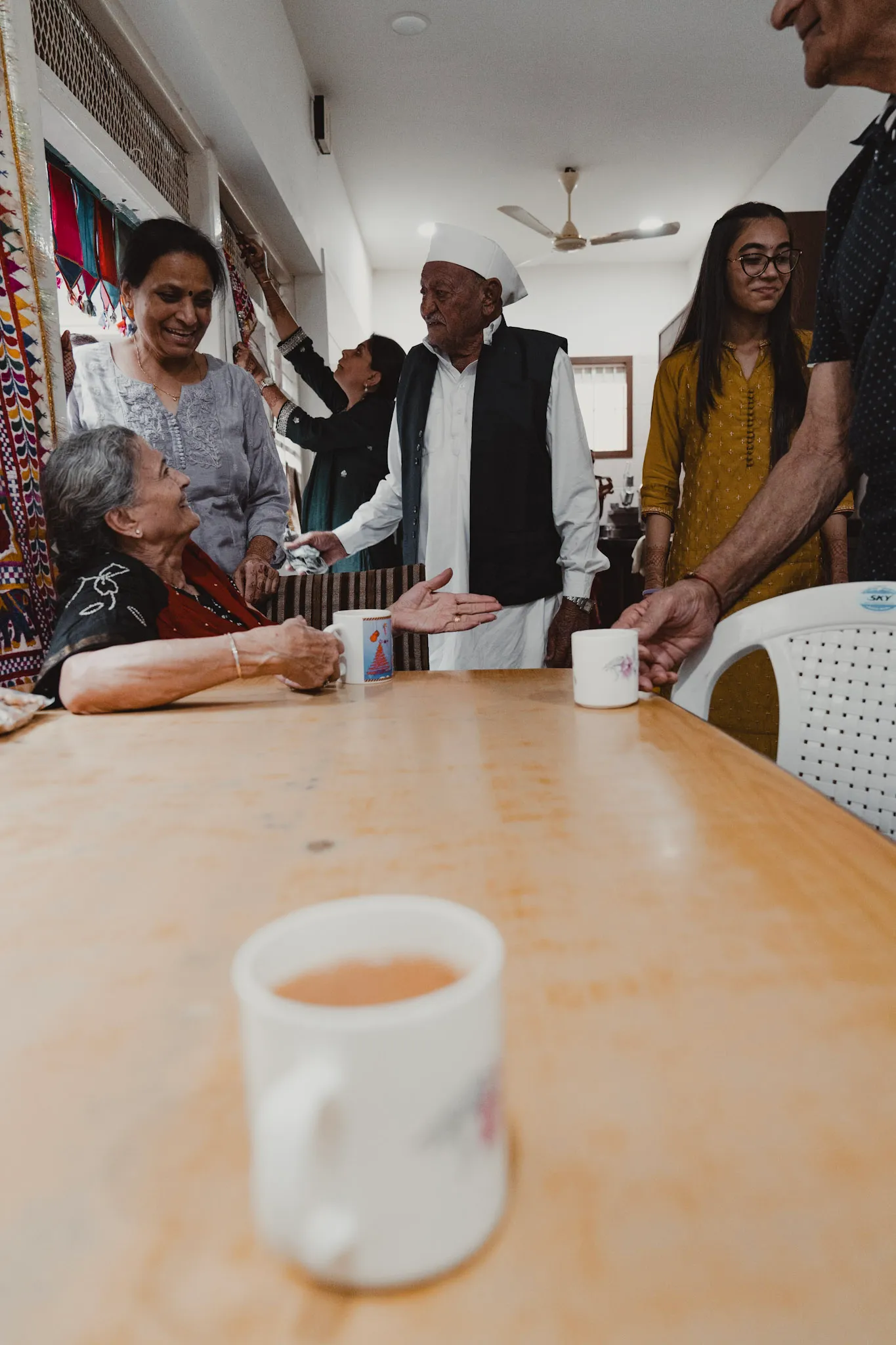 Family gathered around a table with cups of tea.