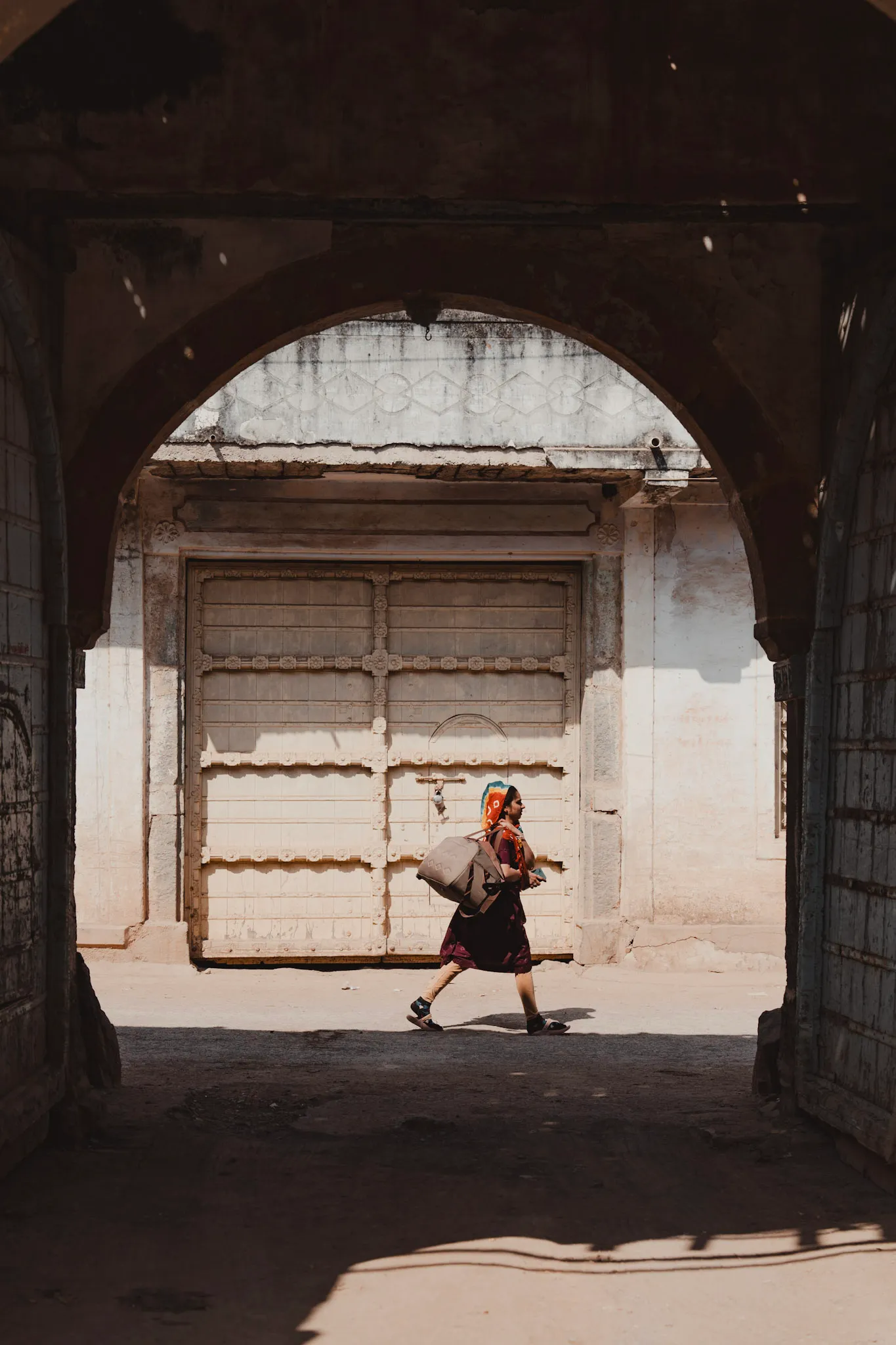 A person walking through an old arched gate.